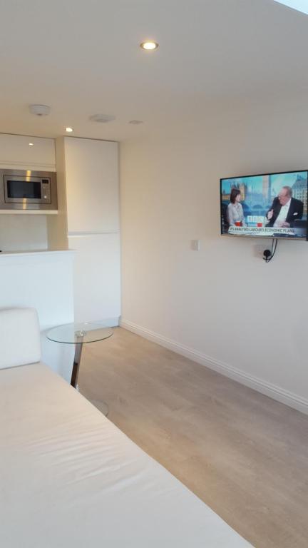 Habitación con mesa y TV en la pared. en Executive Annex - Dunfermline en Dunfermline