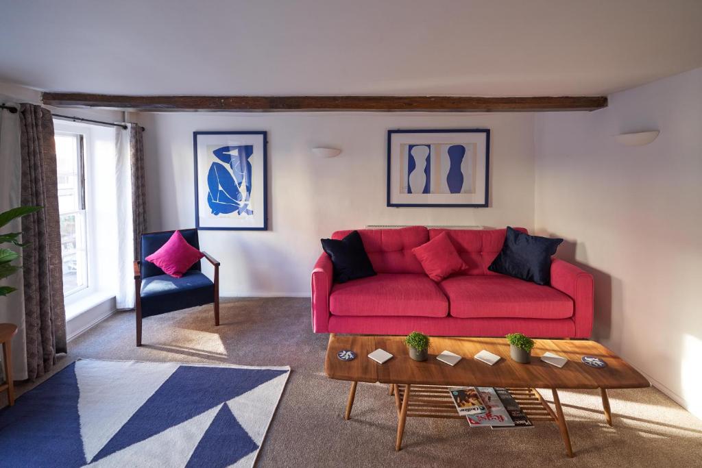 a living room with a red couch and a coffee table at No 88 UPPER ST GILES - Elegant, Stylish Townhouse in Norwich