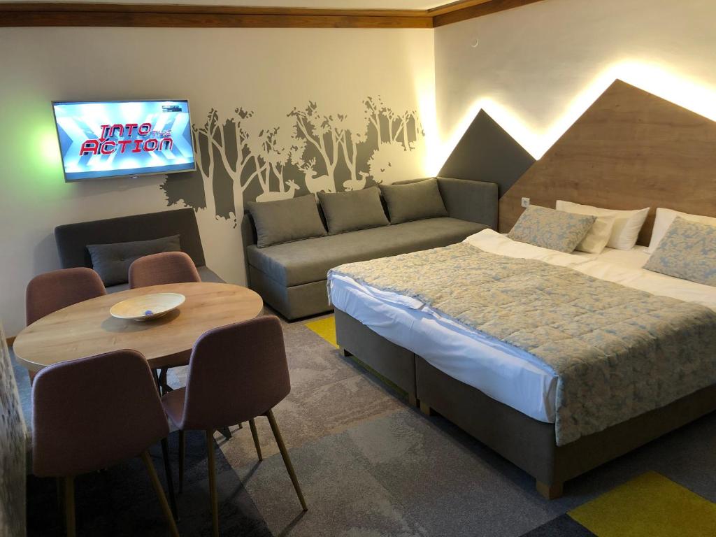 ein Schlafzimmer mit einem Bett, einem Tisch und einem Fernseher in der Unterkunft Apartment 101 - Aparthotel Vucko Jahorina private host in Jahorina