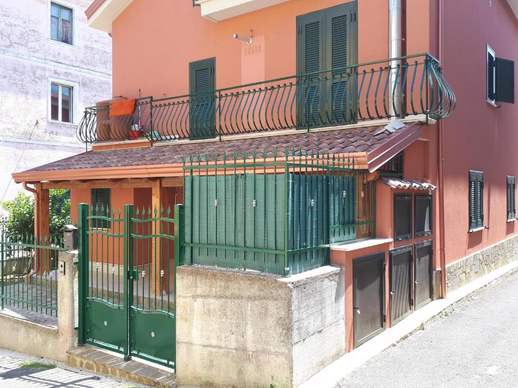 a red building with green doors and a balcony at Villa Rosangela in Agropoli
