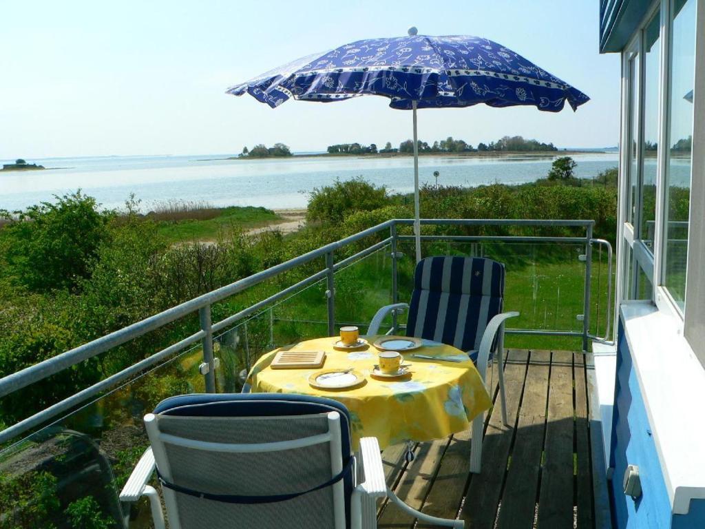 a table and chairs on a balcony with an umbrella at WBHS53001-Die-Ostsee-so-nah in Westerbergen