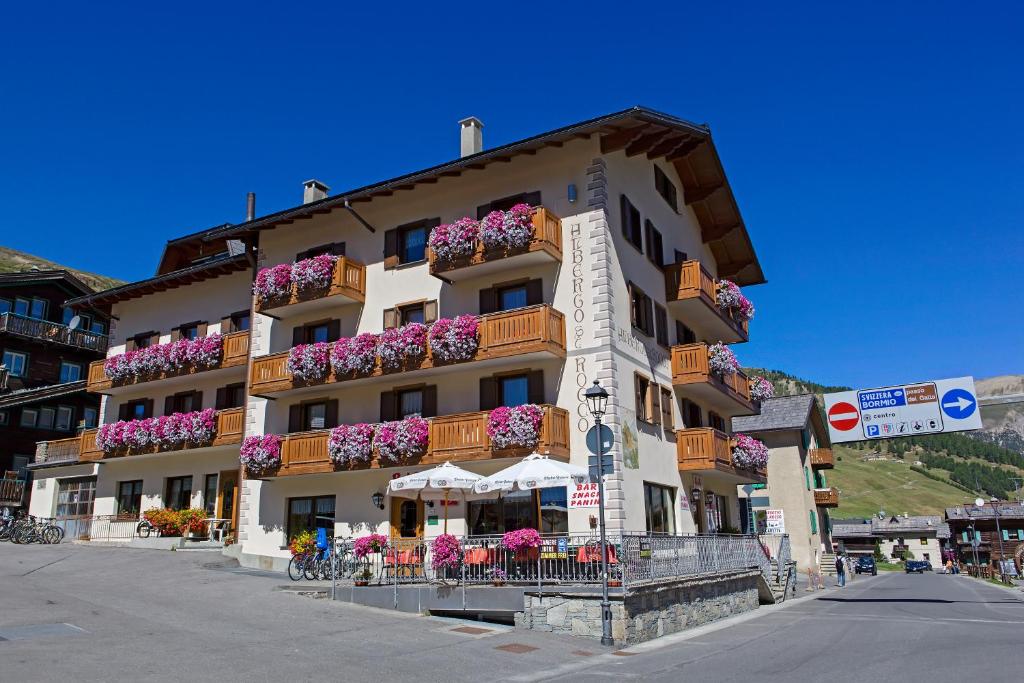 a building with flowers on the balconies on a street at Hotel San Rocco in Livigno