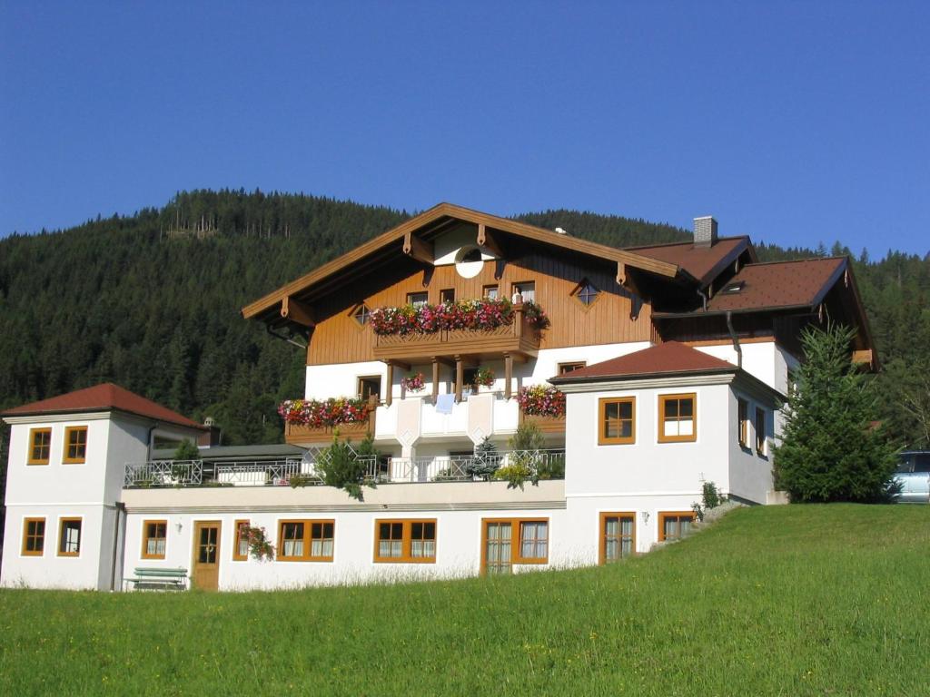 a large white building with a balcony on a hill at Mittersteghof, in Filzmoos