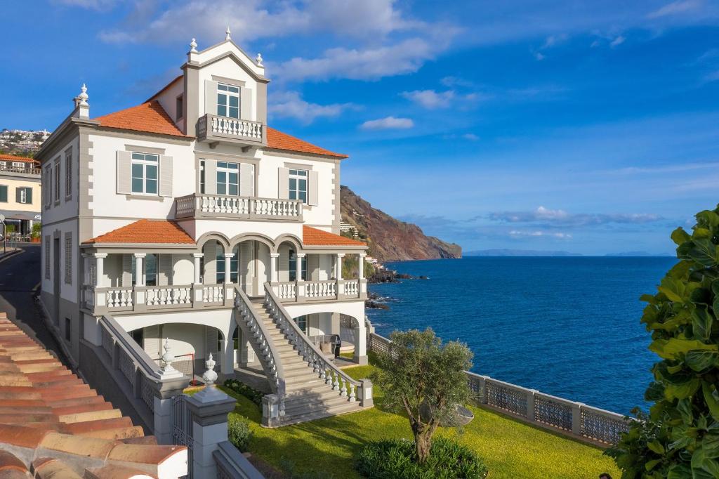 a large white house with a staircase leading to the ocean at Luxury Barreirinha House old town by HR MADEIRA in Funchal