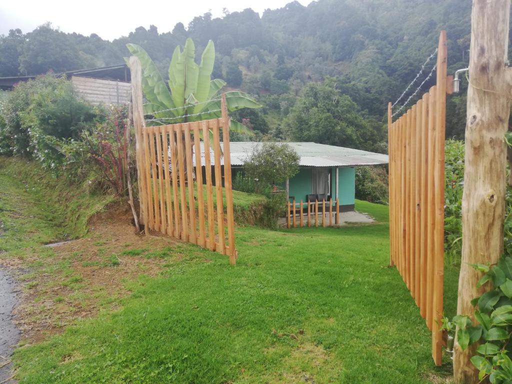 ein Holzzaun vor einem Haus in der Unterkunft Casa #6 cabinas san gerardo in San José