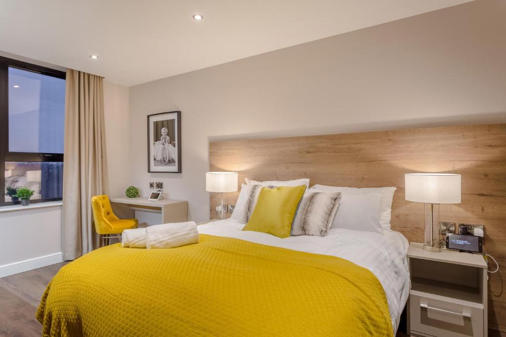 a bedroom with a large bed with a yellow blanket at Dwell City Living in Nottingham