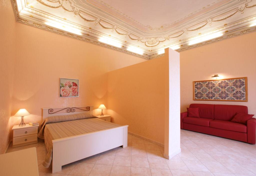 1 dormitorio con 1 cama y 1 sofá rojo en La Dimora dell'800, en Trapani