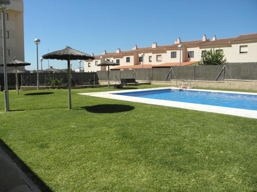 una piscina con sombrilla y hierba en Apartamento en Jerez de la Frontera en Jerez de la Frontera