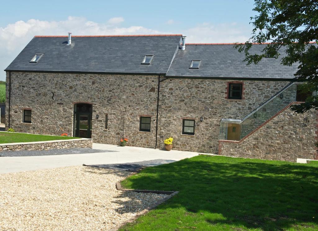 un grand bâtiment en briques avec un toit noir dans l'établissement Kidwelly Farm Cottage, à Kidwelly