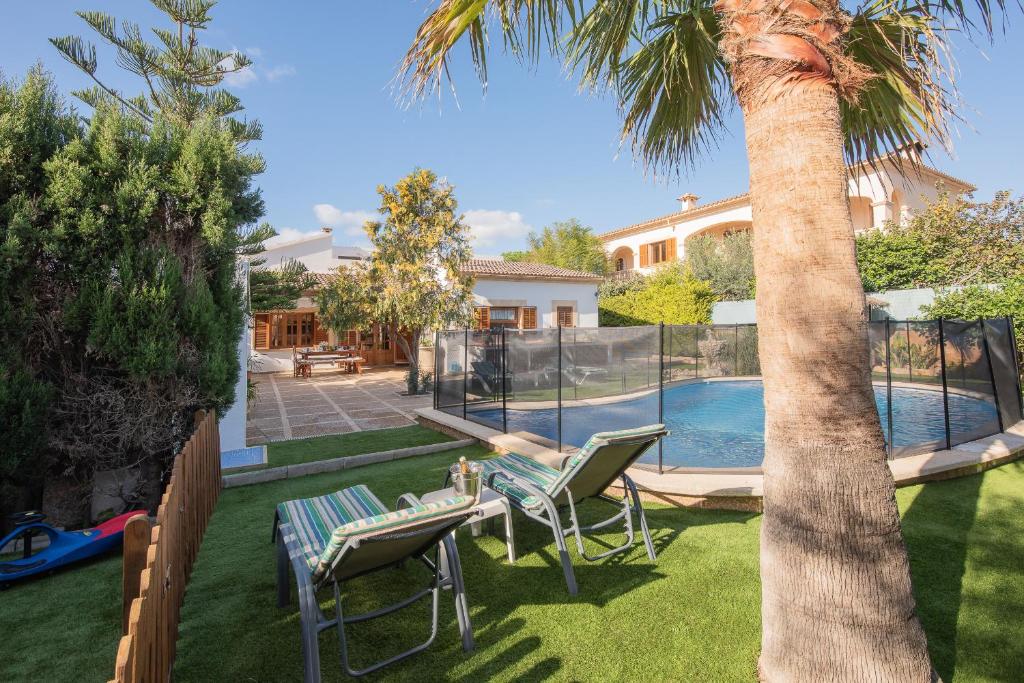 a yard with a palm tree and chairs and a swimming pool at Villa Anfos in Sa Ràpita