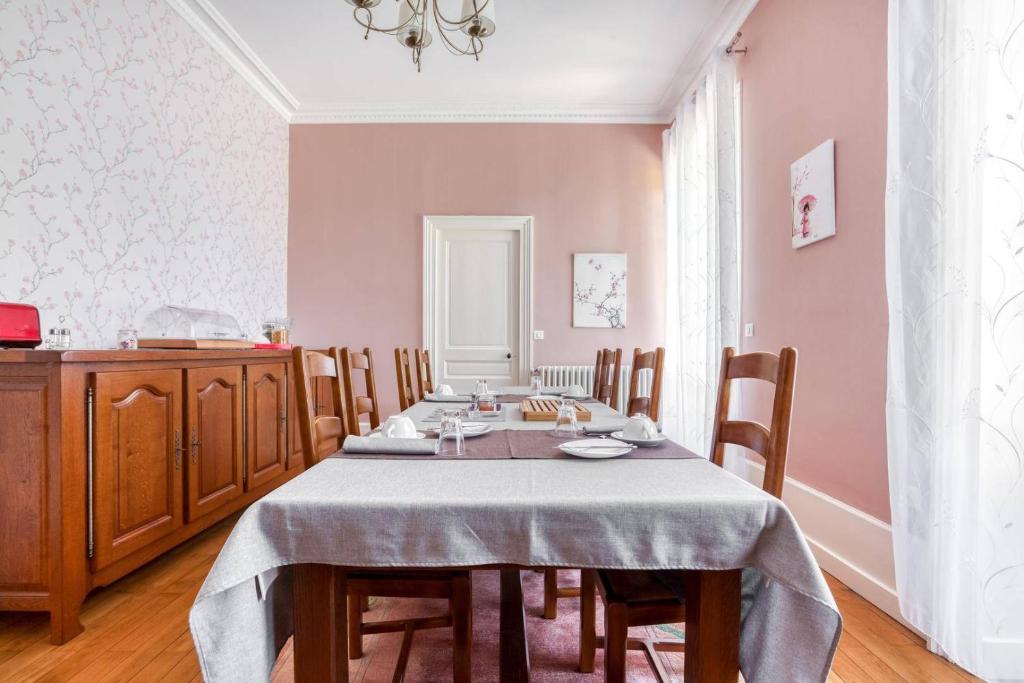 ein Esszimmer mit einem Tisch und Stühlen sowie rosafarbenen Wänden in der Unterkunft Le Clos des Pervenches in Jassans-Riottier