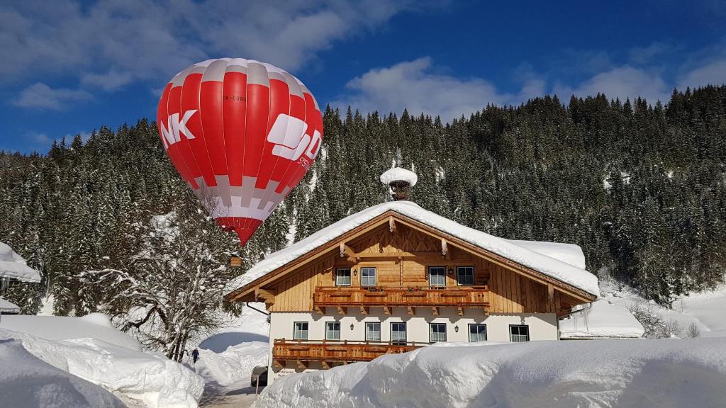 a hot air balloon flying over a house in the snow at Bauernhof Krahlehenhof in Filzmoos