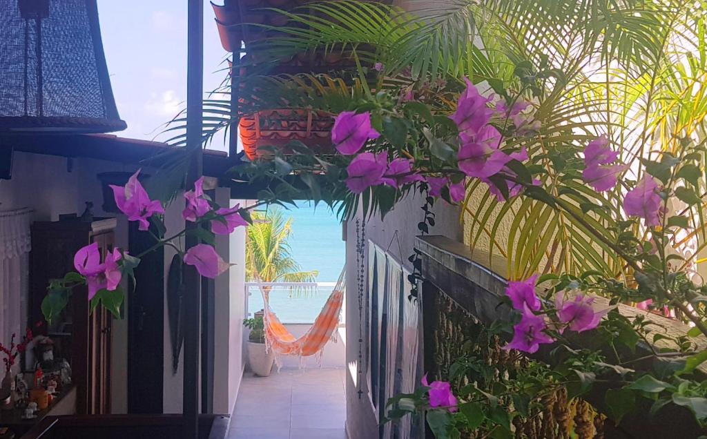 una vista sulla spiaggia da una casa con fiori viola di Pousada Recanto da Família a Natal