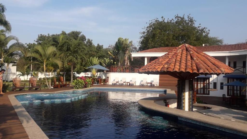 una piscina con sombrilla junto a una casa en Casa Ceibo Hotel, en Bahía de Caráquez