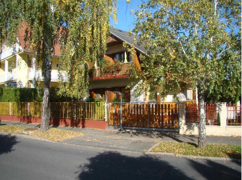 ヘーヴィーズにあるVirágoskert Apartmanの塀と木の前の家