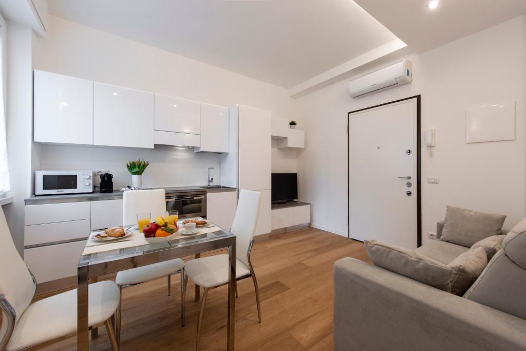 eine Küche und ein Wohnzimmer mit einem Tisch und einem Sofa in der Unterkunft BnButler Friuli, 24 - Porta Romana Apartment in Mailand