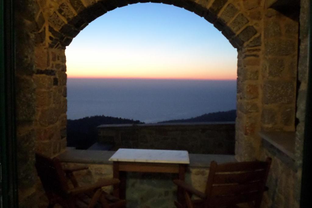 une arche dans un bâtiment avec une table et un coucher de soleil dans l'établissement To Asteri, à Avgonyma
