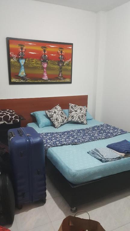 a bedroom with a bed with a suitcase and a painting at Apartamento CERCA AEROPUERTO, Fotos y huellas para visa americana, embajada EEUU in Bogotá