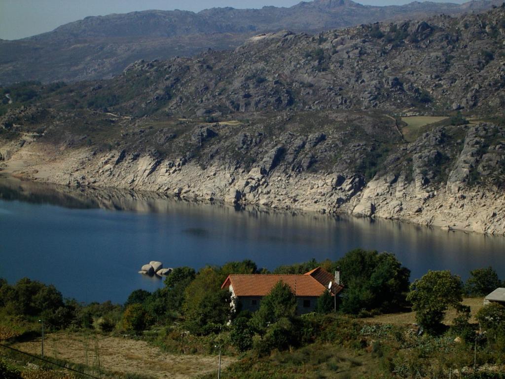 a house on the side of a lake with a mountain at Oficina Do Joe Guesthouse in Outeiro