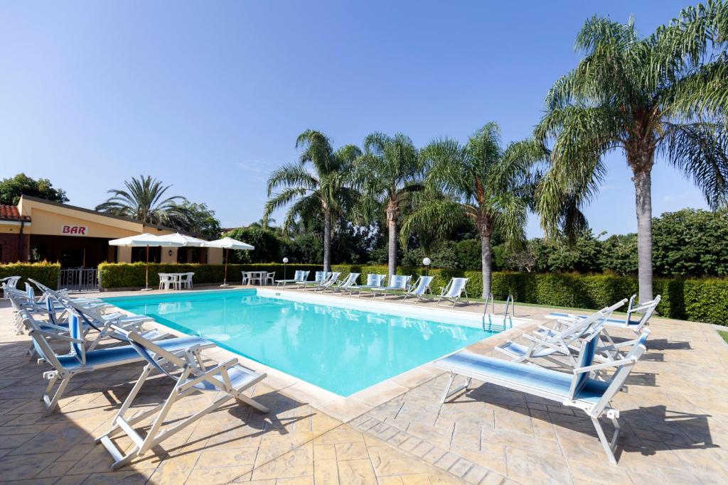 una piscina con tumbonas y palmeras en Hotel La Fattoria Sul Mare, en Capo Vaticano