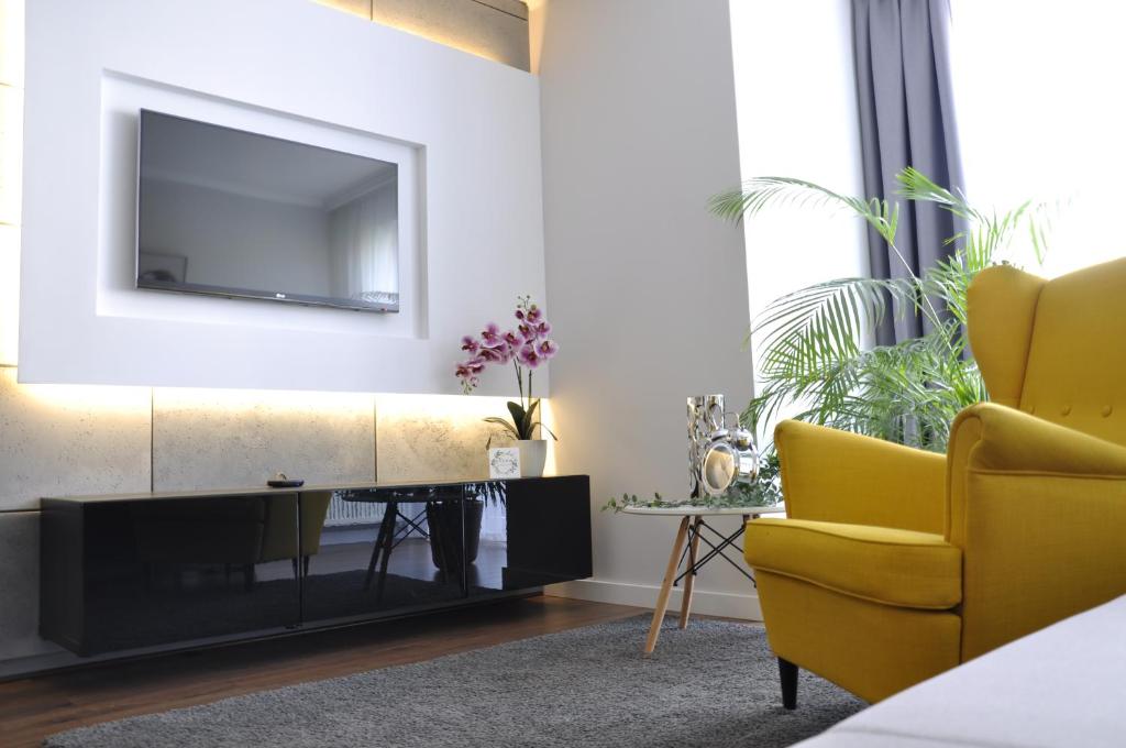 a living room with a television and a yellow chair at Apartament na Tęczowej in Wrocław