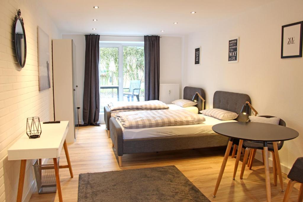 a bedroom with a bed and a table and a table at Moderne 1-Zimmer Wohnung mit Terasse, Küche, Bad mit Dusche, TV & WIFI in Burgwedel