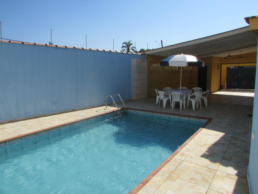 - une piscine avec une table et un parasol dans l'établissement Casa c/ Piscina - Ampla e Arejada Balneário Gaivota - 300 mts da Praia, à Itanhaém