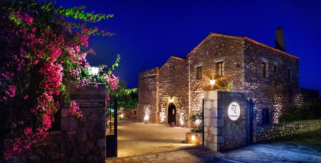 an old stone building with a clock on it at night at Guesthouse Toxotis in Pyrgos Dirou