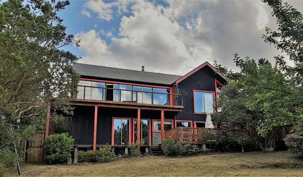 a black house with large glass windows and trees at Hostel Torobayo in Valdivia