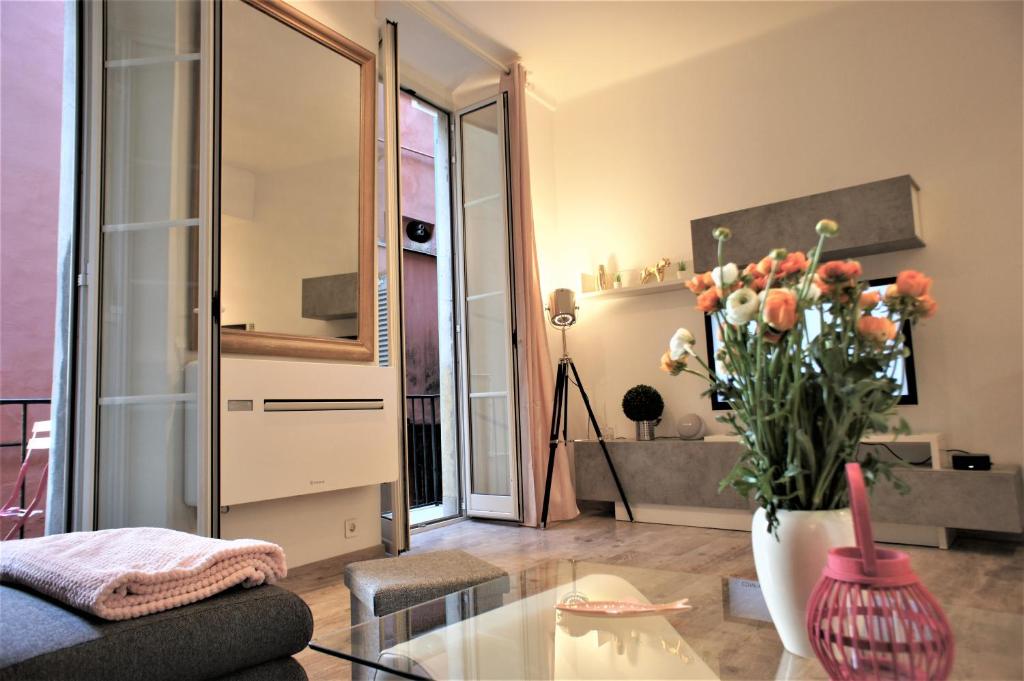 ein Wohnzimmer mit einem Tisch und einer Vase aus Blumen in der Unterkunft Ze Perfect Place - Superbe appartement 2 Chb - AC - Saleya - Marché aux fleurs in Nizza