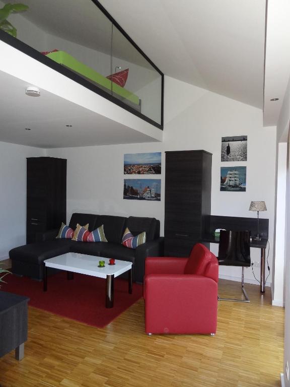 a living room with a black couch and a red chair at Backbord Und Steuerbord in Stralsund