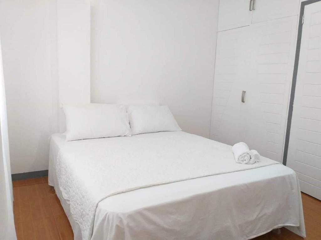 a white bedroom with a bed with white sheets at Diodeth's Apartments in Butuan