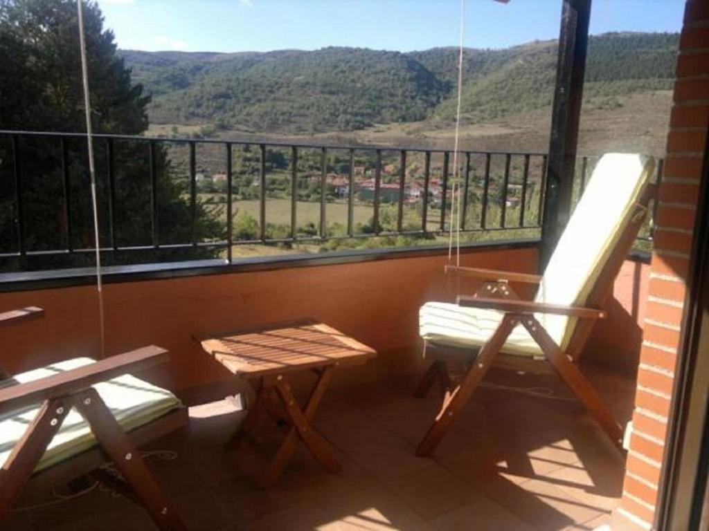 Un balcón con 2 sillas, una mesa y un banco en Apartamento Duplex en Ezcaray, en Zorraquín