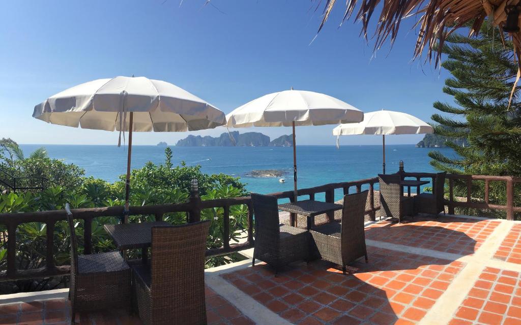 a group of tables and chairs with umbrellas overlooking the ocean at HIP Seaview Resort @ Phi Phi in Phi Phi Don