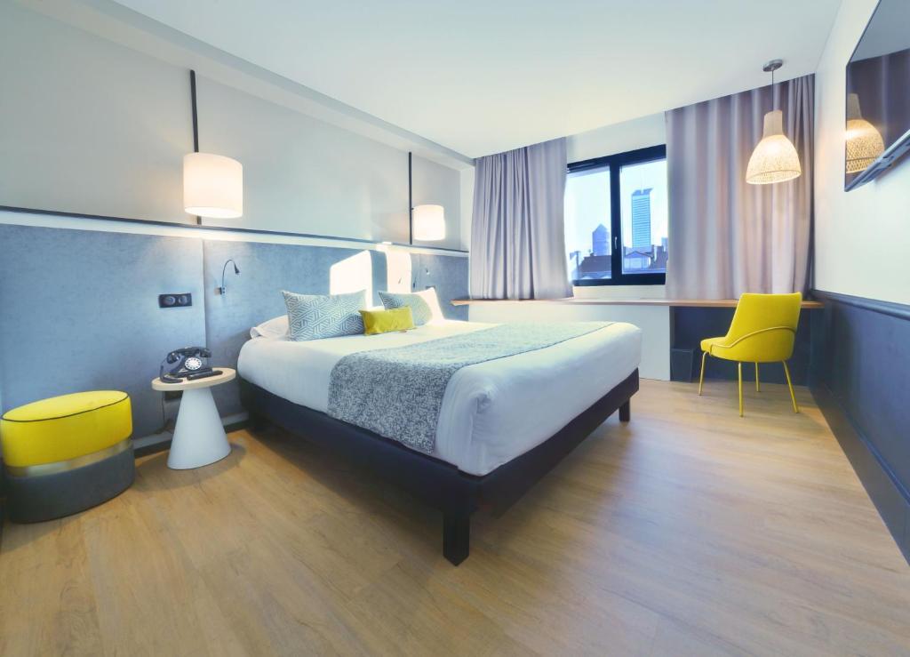 a hotel room with a bed and two yellow chairs at Hôtel Le Roosevelt Lyon in Lyon