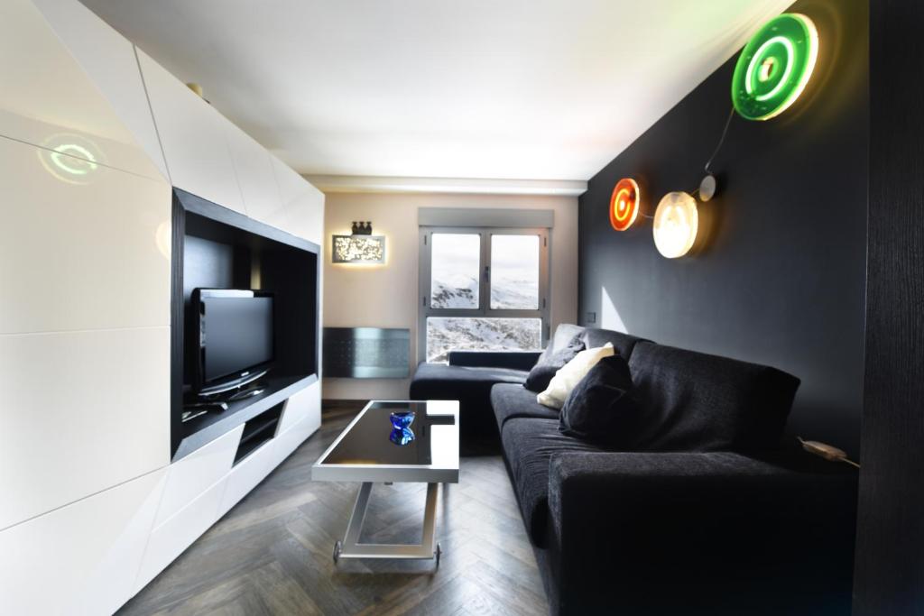 un soggiorno con un divano nero e una TV di El Semáforo - Lujo, Confort y Vistas Espectaculares a Sierra Nevada