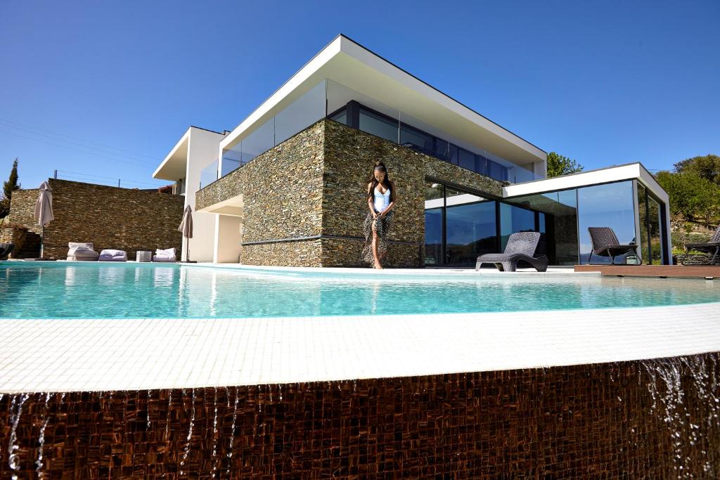 a woman is standing in front of a swimming pool at Quinta Rainha Santa Mafalda in Pinhão