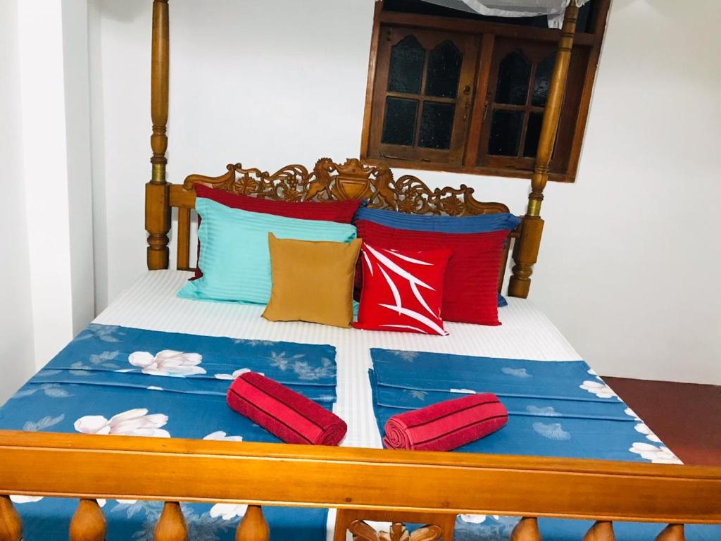 a bed with red and blue pillows on it at SunshineJP Guest House and bick rentel in Weligama