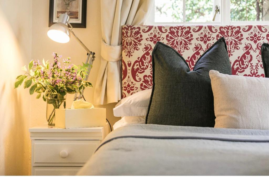 a bedroom with a bed with pillows and a window at Waterfall Cottages in Johannesburg