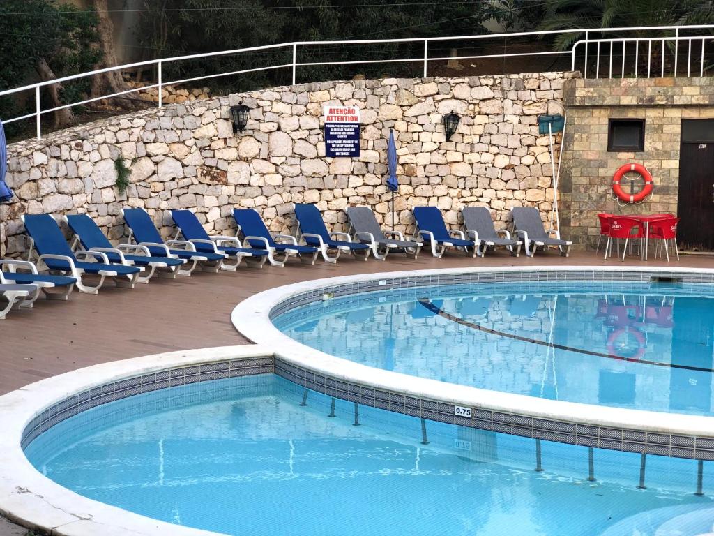 una gran piscina con sillas y una mesa en Squash Club Apartamentos, en Portimão