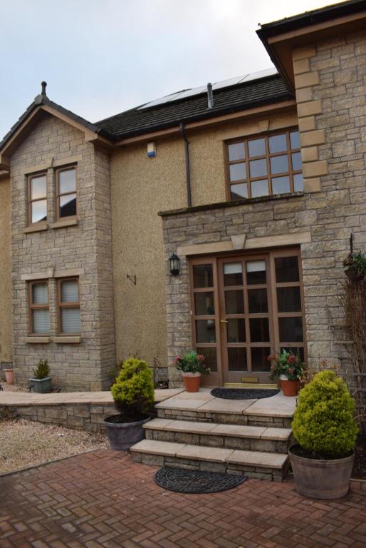 a brick house with potted plants in front of it at Kelpies Serviced Apartments Kavanagh- 5 Bedrooms in Bathgate