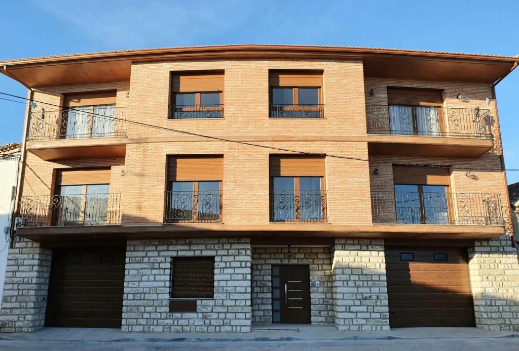 Edificio de ladrillo marrón con ventanas y balcón en Amanece Monegrillo Apartamentos, en Monegrillo