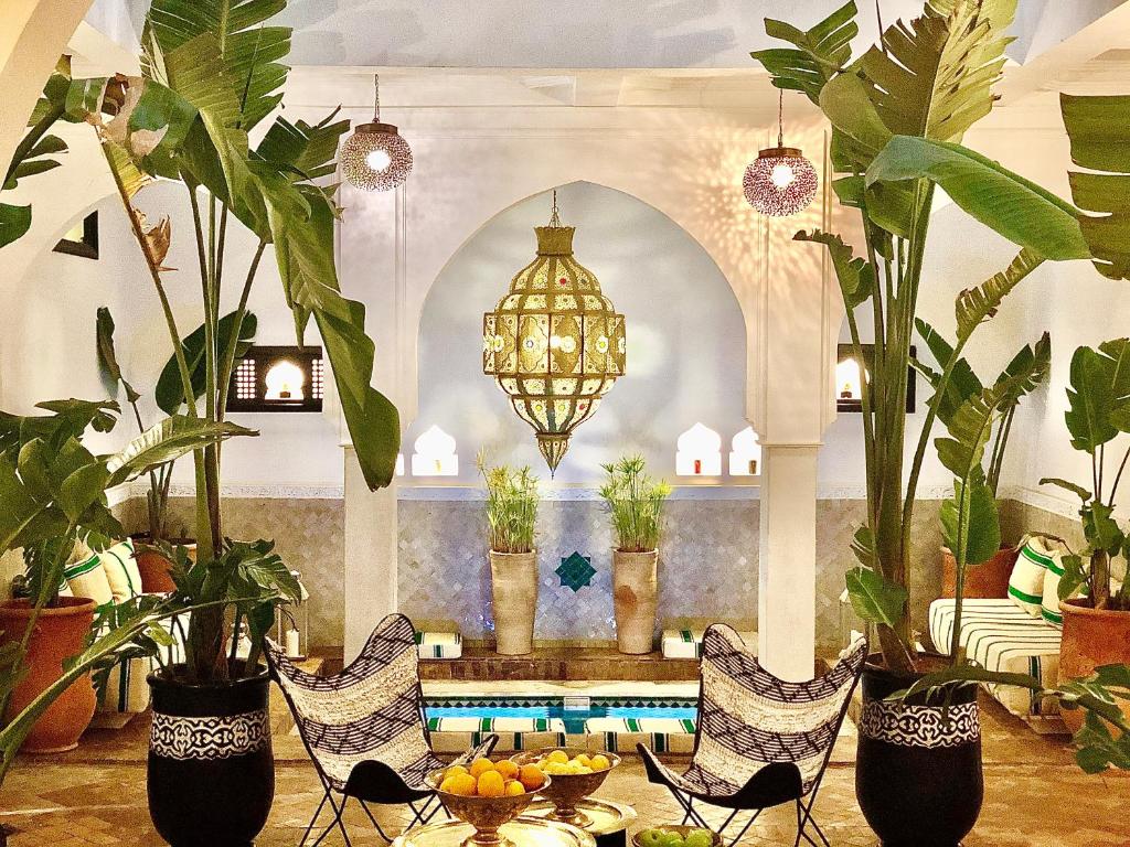 um átrio com plantas, uma mesa e um lustre em Maison Chafia Boutique Hôtel & Spa em Marraquexe