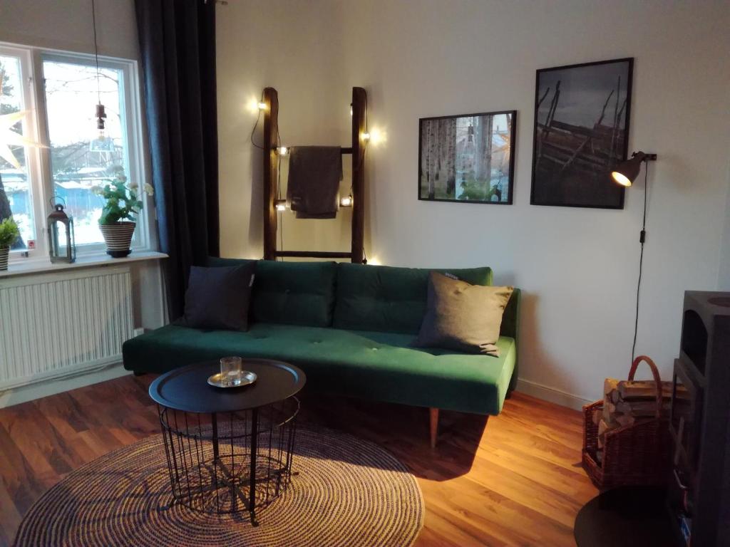 a living room with a green couch and a table at Gårdshuset in Söderhamn