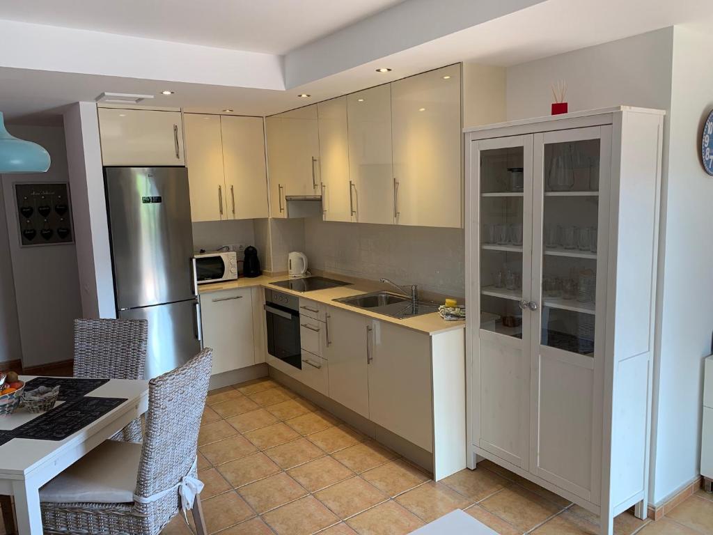 a kitchen with white cabinets and a table and a refrigerator at Casa Achille in Cotillo