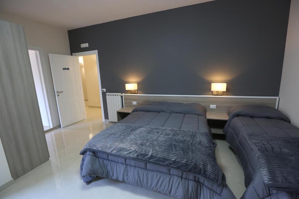sypialnia z 2 łóżkami i 2 lampkami na ścianie w obiekcie COSTA APARTMENT NAPLES w mieście Napoli