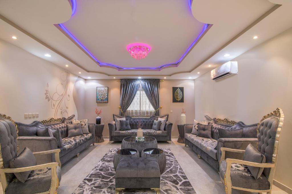 una sala de estar con sofás y una lámpara de araña. en BayatAbha, en Abha