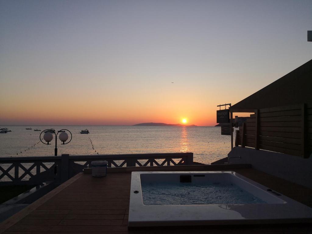 a sunset over the ocean with a swimming pool at LENICO Seafront Villa in Agia Pelagia