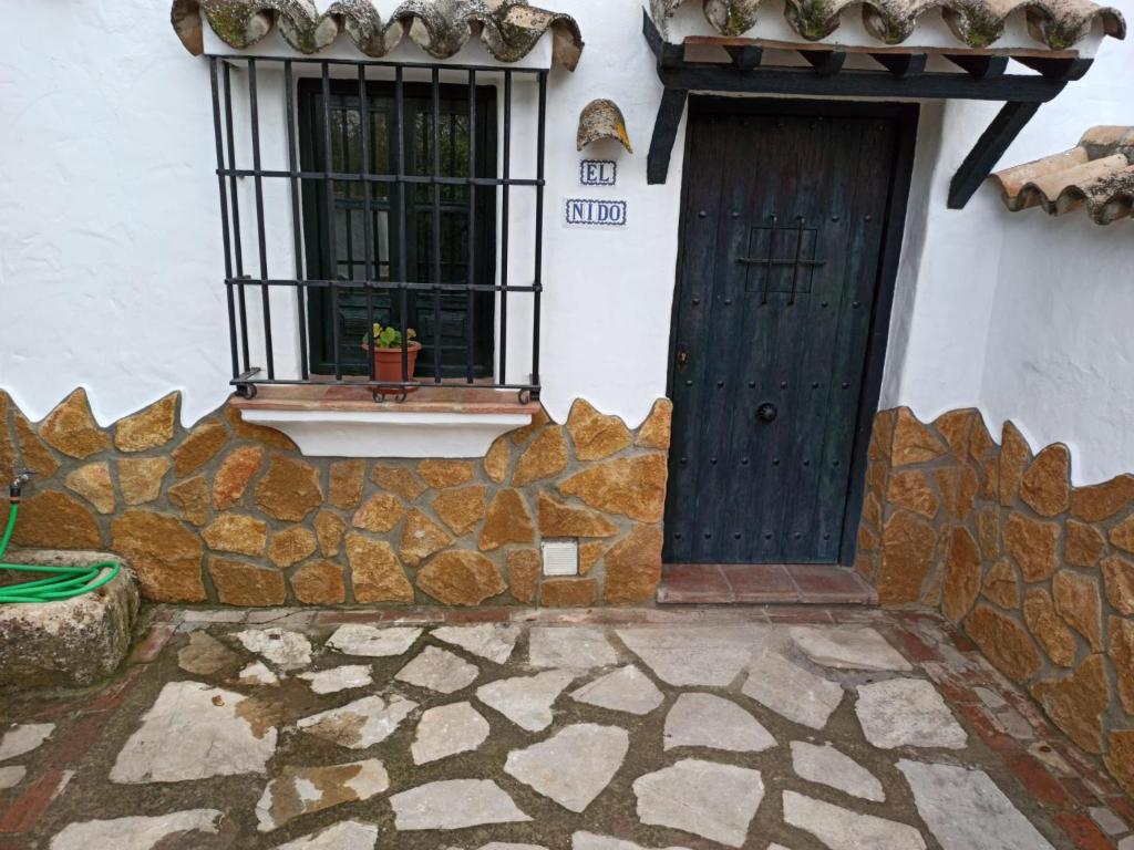 a house with a black door and a window at El Nido in Zahara de la Sierra