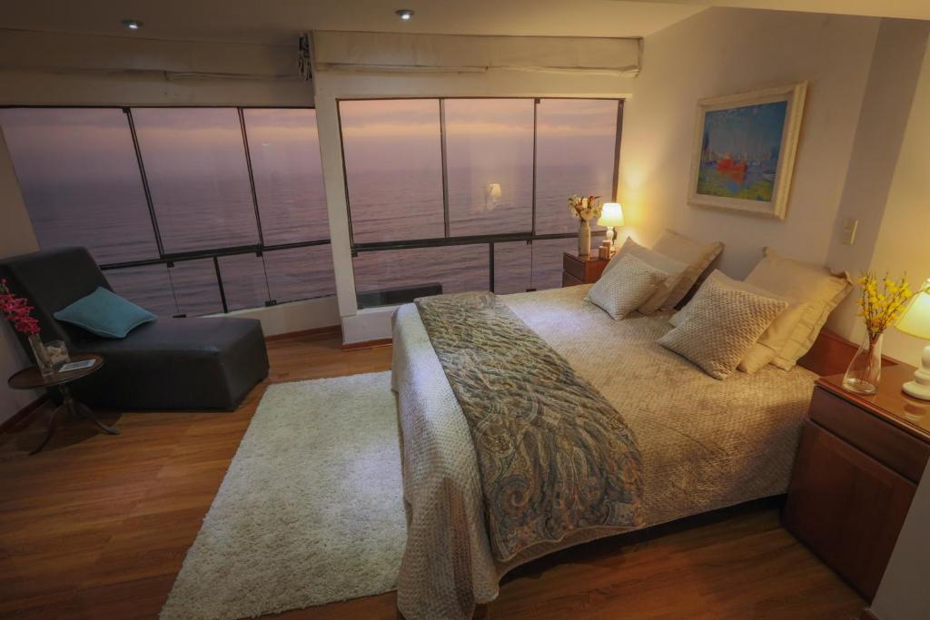 a bedroom with a large bed and a chair at Oceanfront Penthouse in Miraflores in Lima